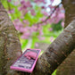 Vegan White Chocolate with Pink Raspberry & Almond laying on top of some branches of a tree with beautiful pink flowers
